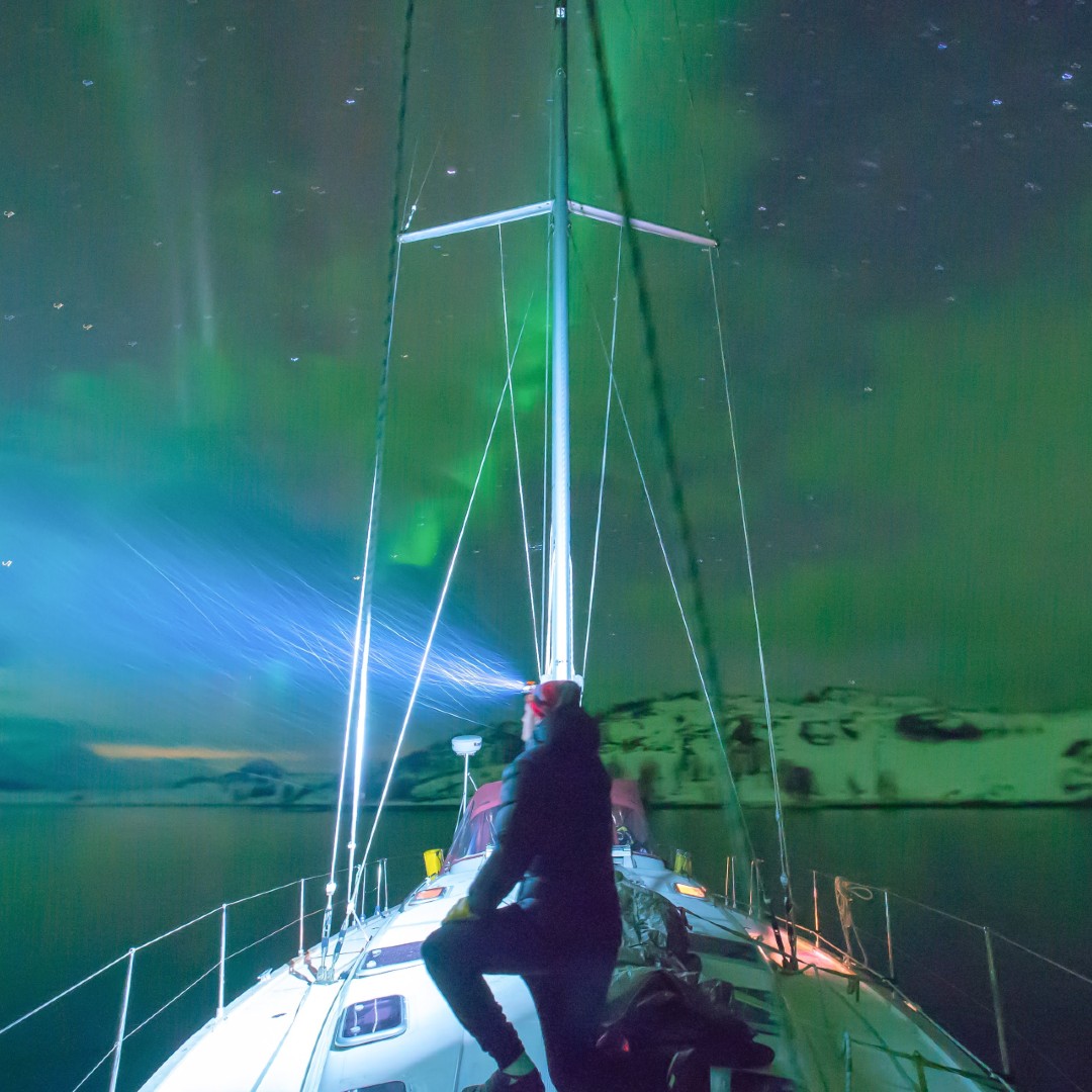 Snowboarder watching Northern Lights from sailboat