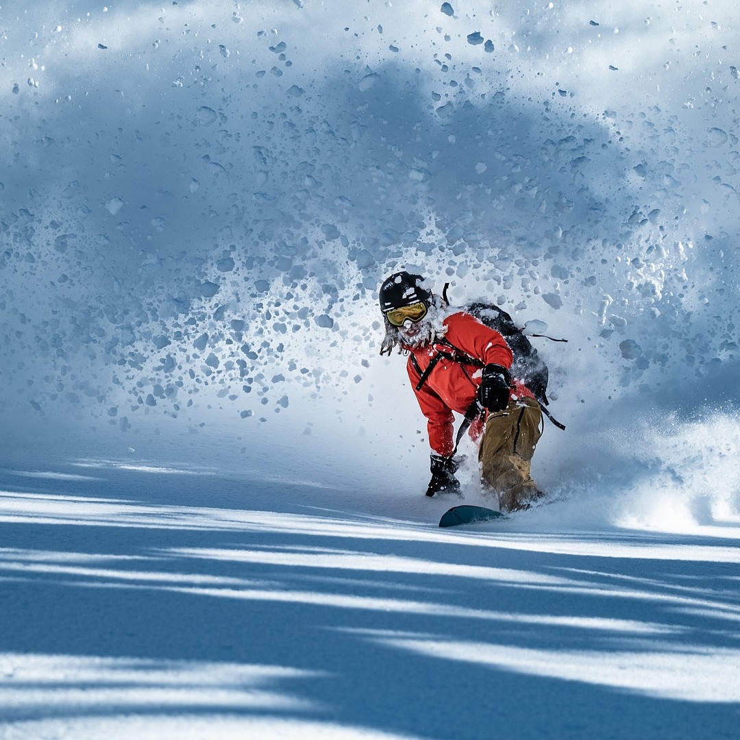Snowboarder riding powder in Furano