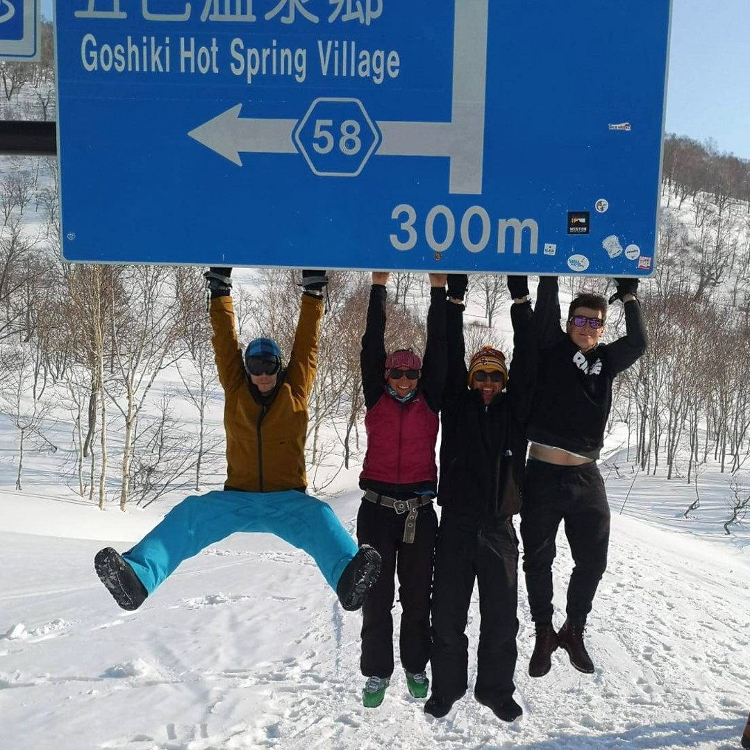 Snowboarders hanging on road sign thanks to thick snow cover